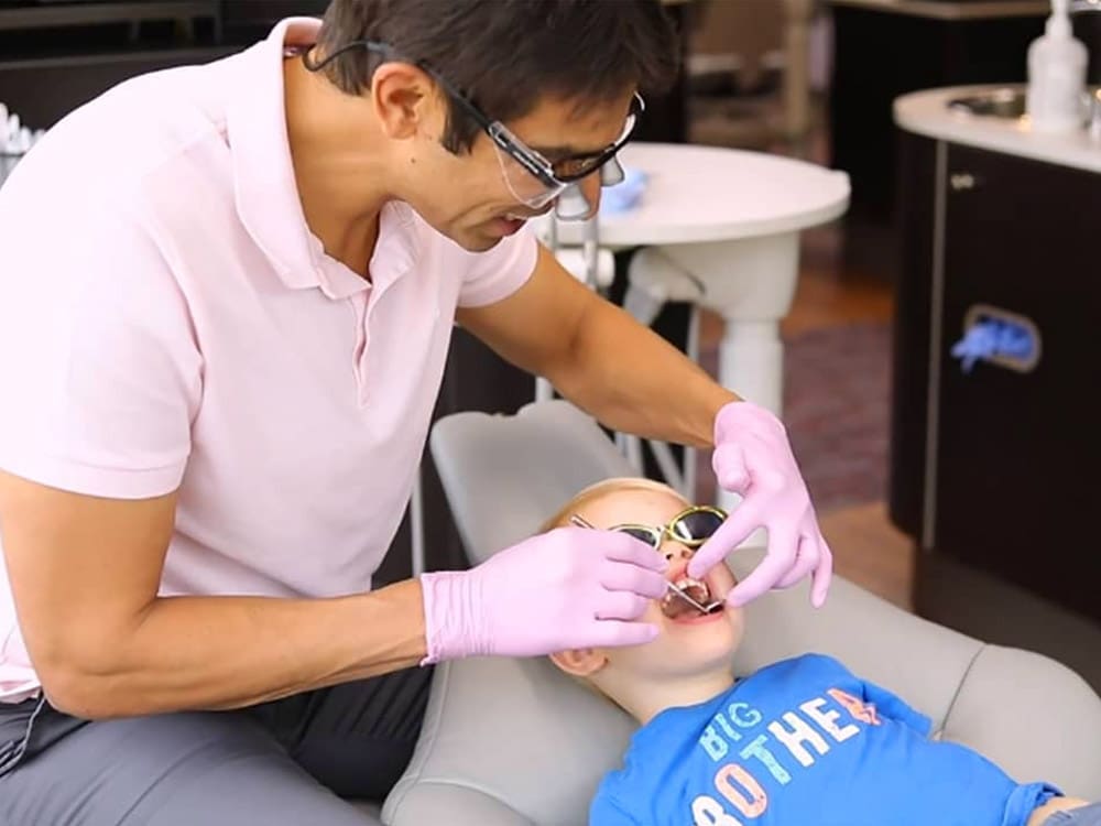 Dentist examining the teeth of a young boy Pediatric Dentist - Trained to work with the kids