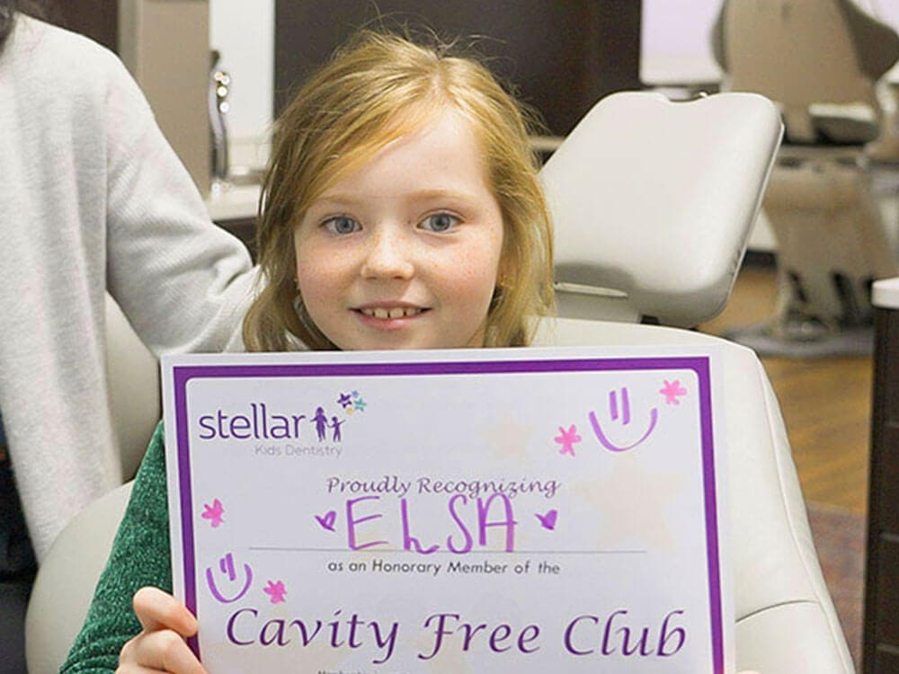 Child holding Cavity Free Club certificate at Stellar Kids Dentistry.