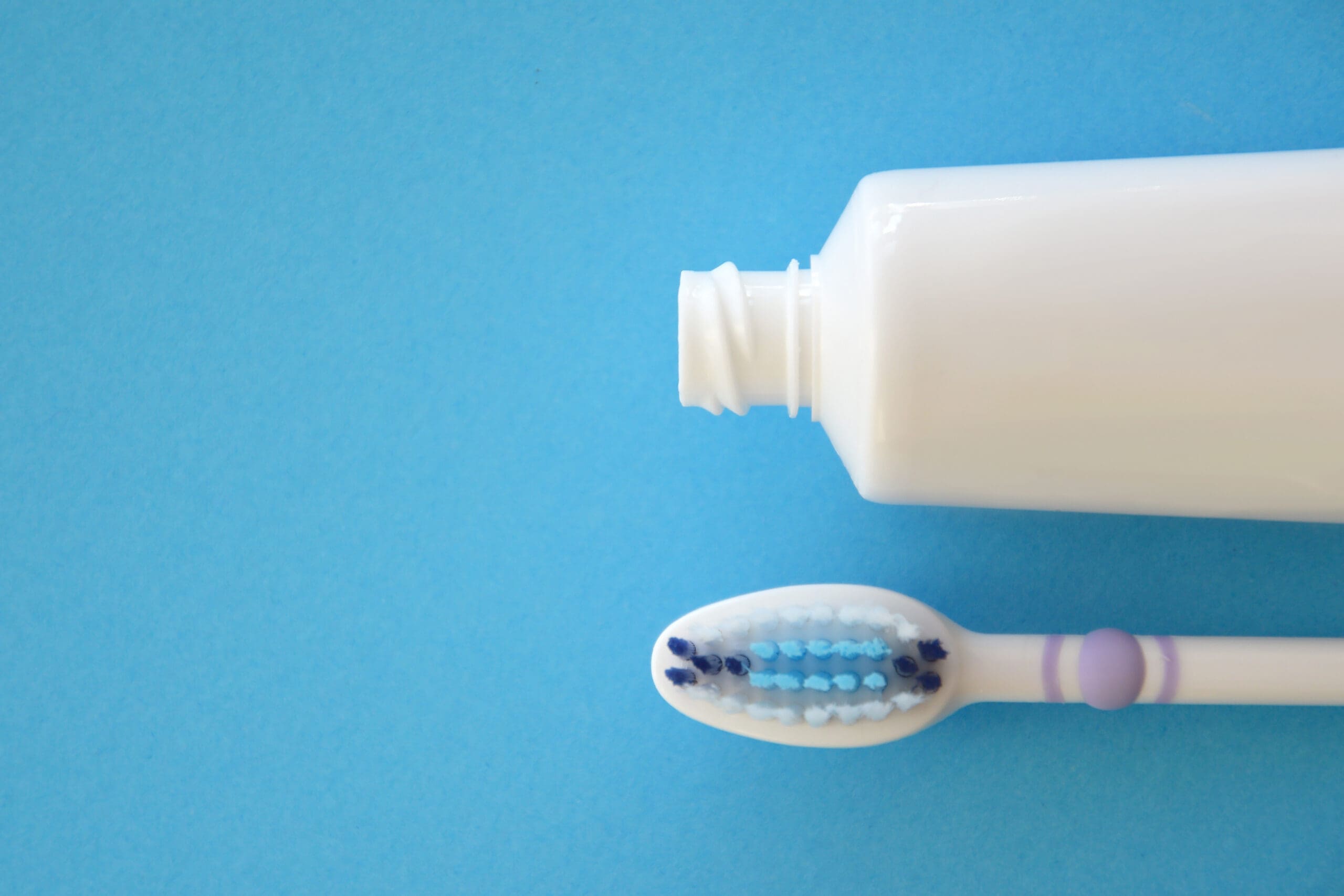 Toothbrush with toothpaste on blue paper background toothbrush and toothpaste